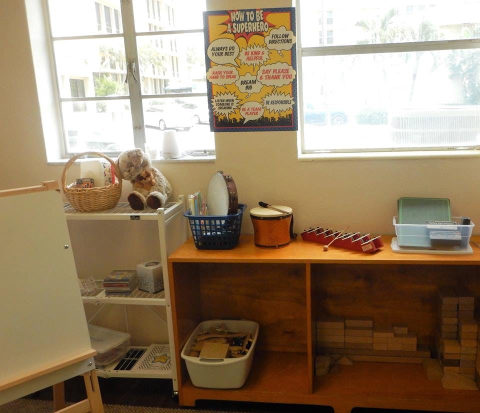 Classroom with shelves of toys and musical instruments, whiteboard, and windows