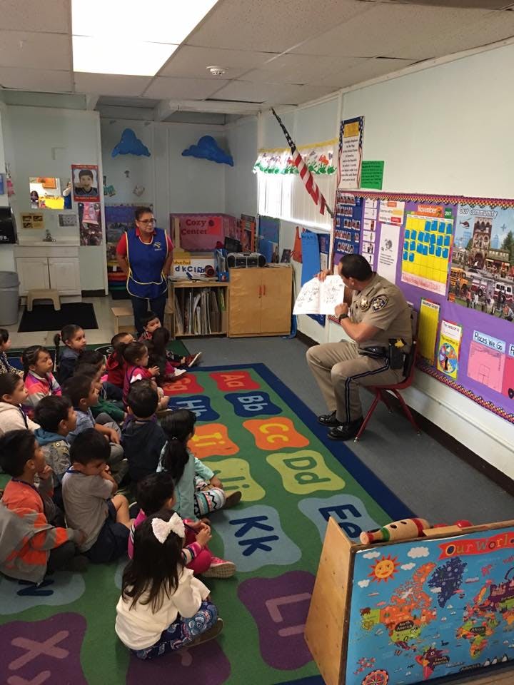 Person in uniform reading to children in a classroom