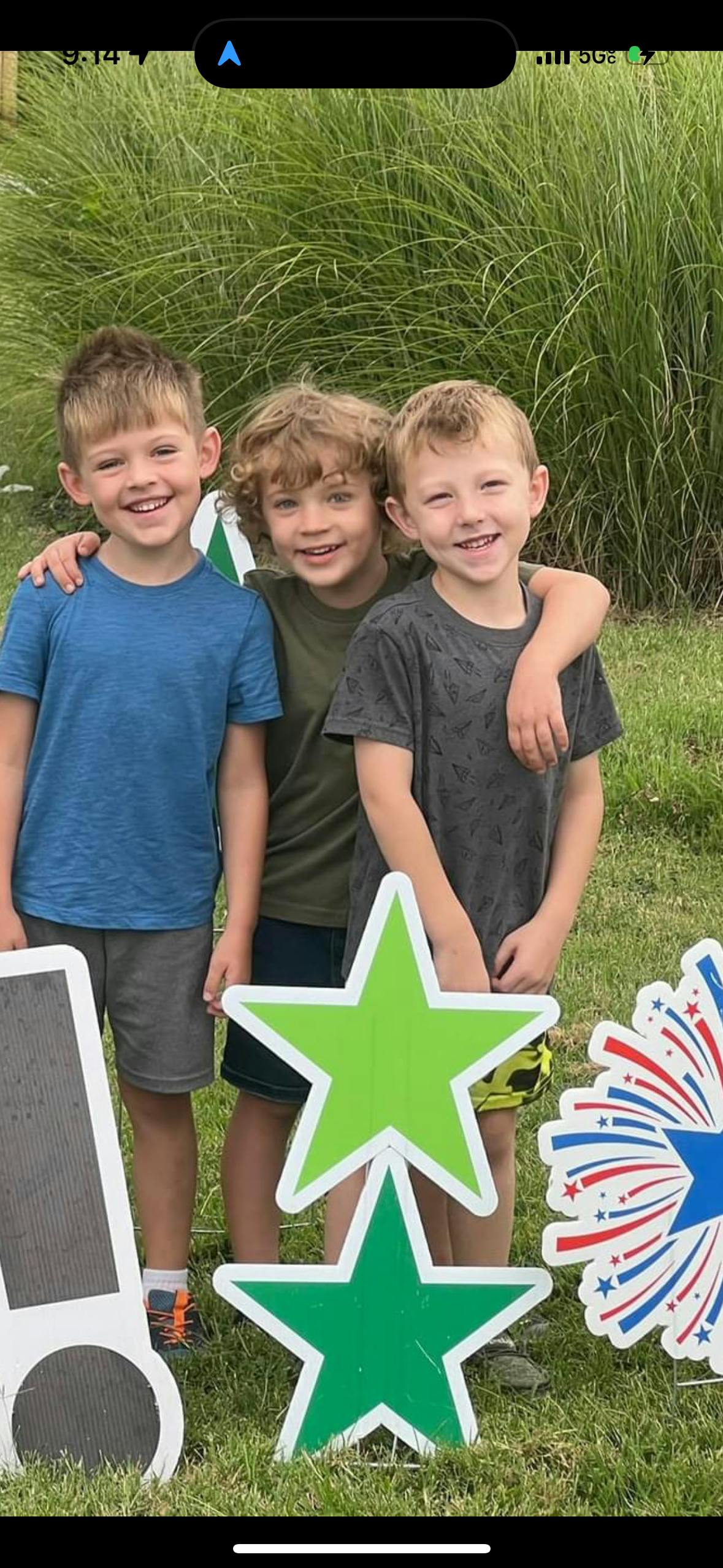 Three children standing together outdoors with decorative stars