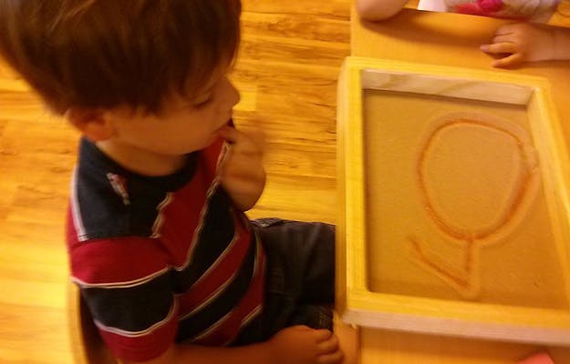 Child looking at a sand tray with a drawing