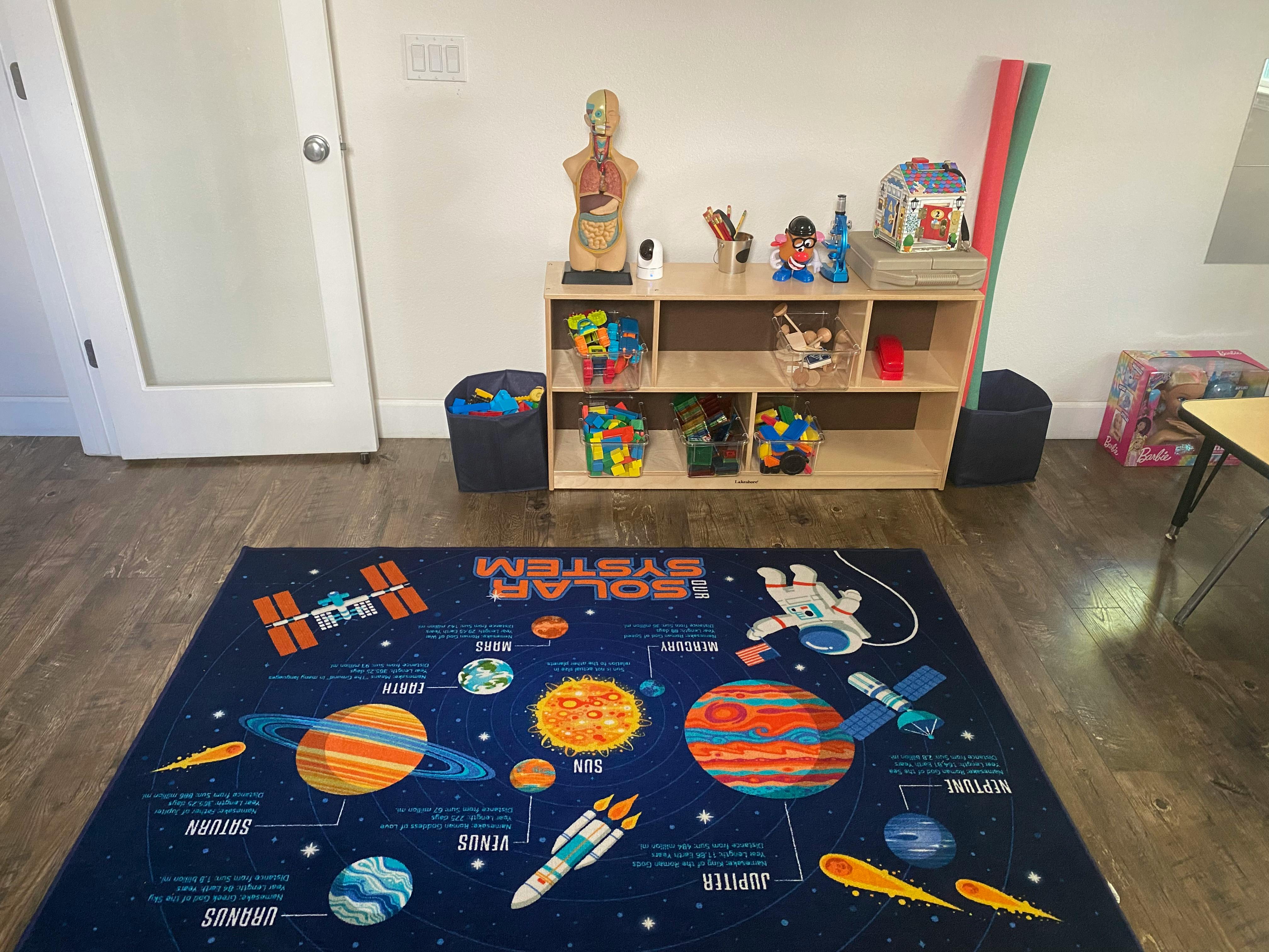 Solar System rug on a wooden floor in a room with a shelf of toys