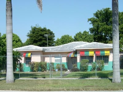 House with colorful striped awnings and a chain link fence