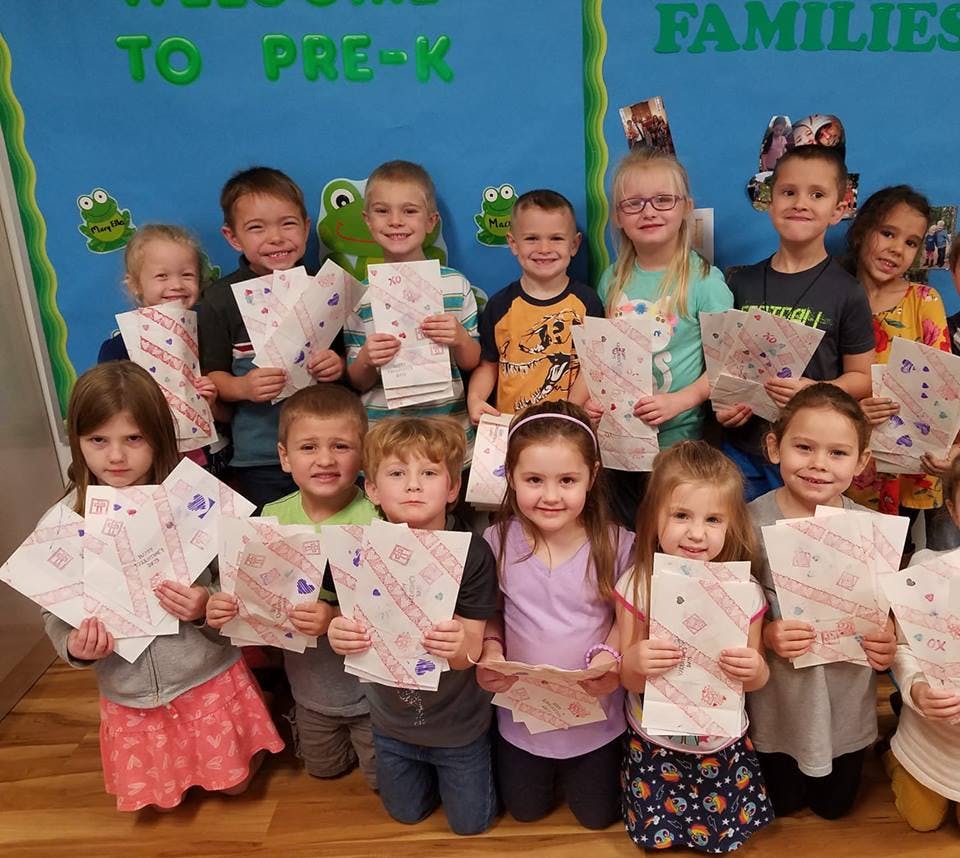 Group of children holding up papers in a classroom