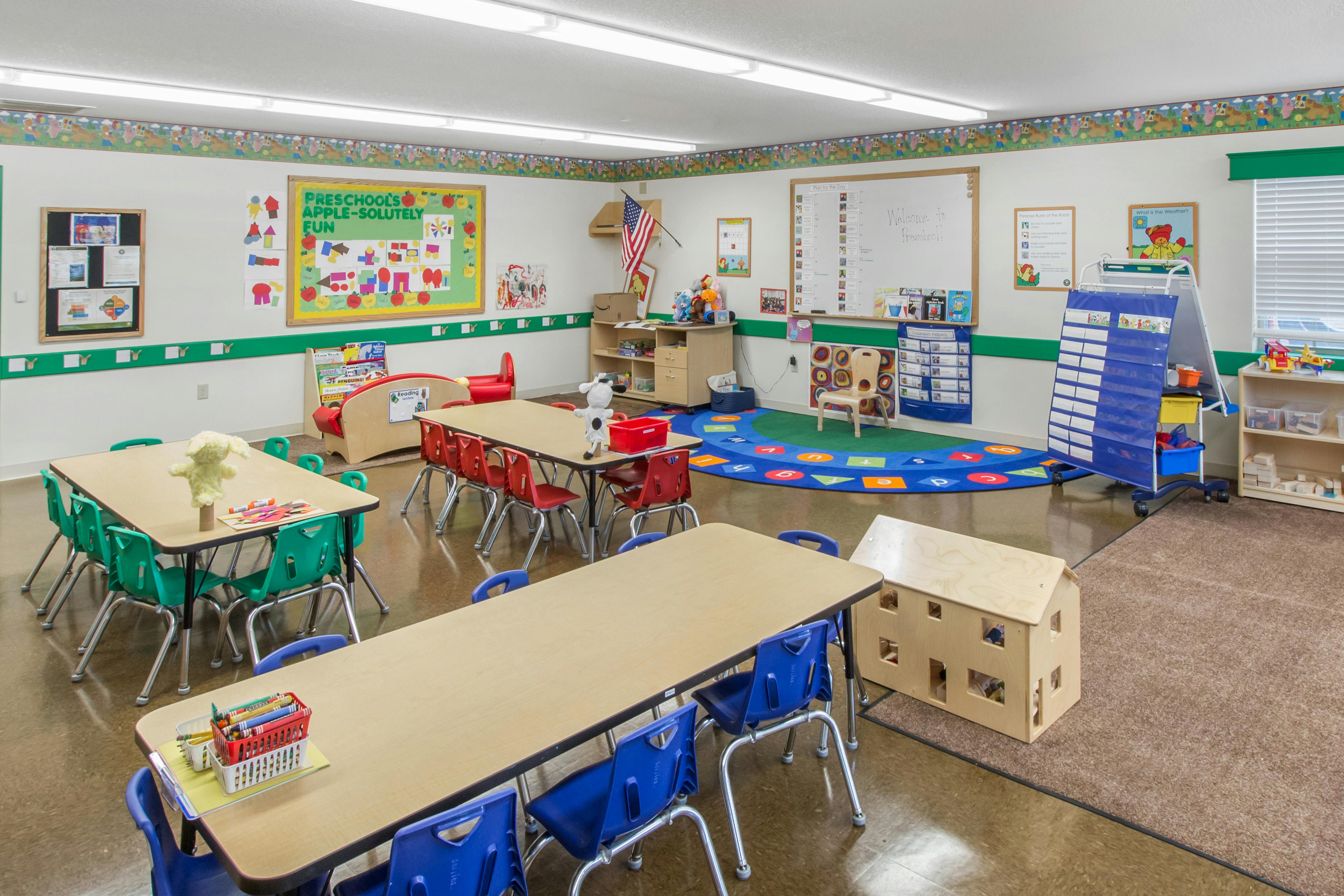 A colorful preschool classroom with small tables, chairs, and educational posters
