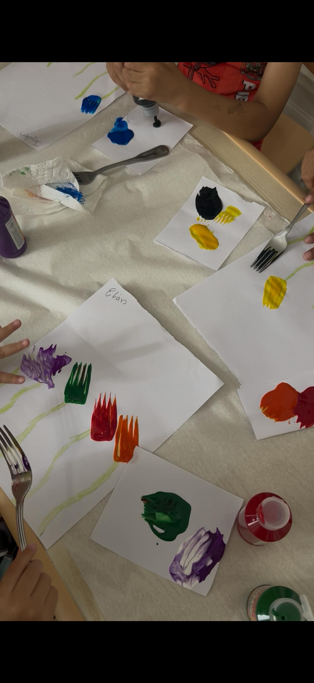People using forks to paint flower shapes on paper