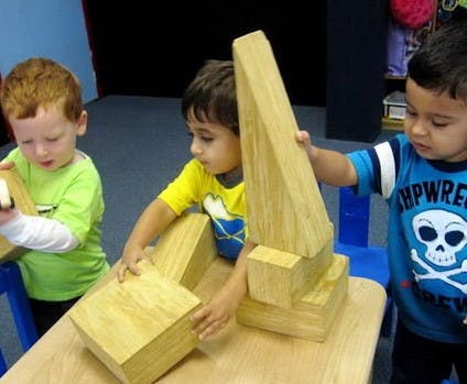 Three children playing with wooden blocks