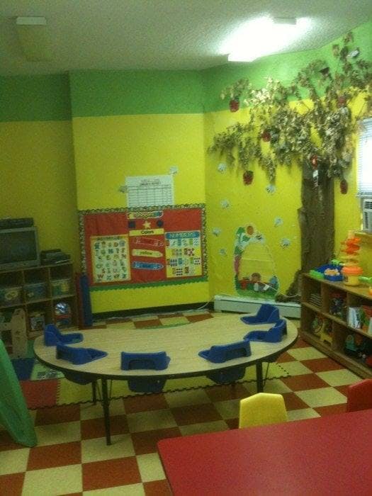 Classroom with a round table and chairs, decorated with a tree on the wall