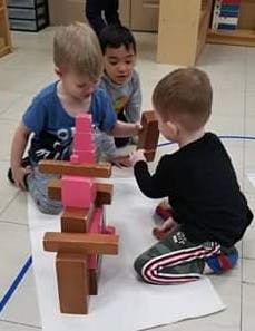 Three children playing with wooden blocks