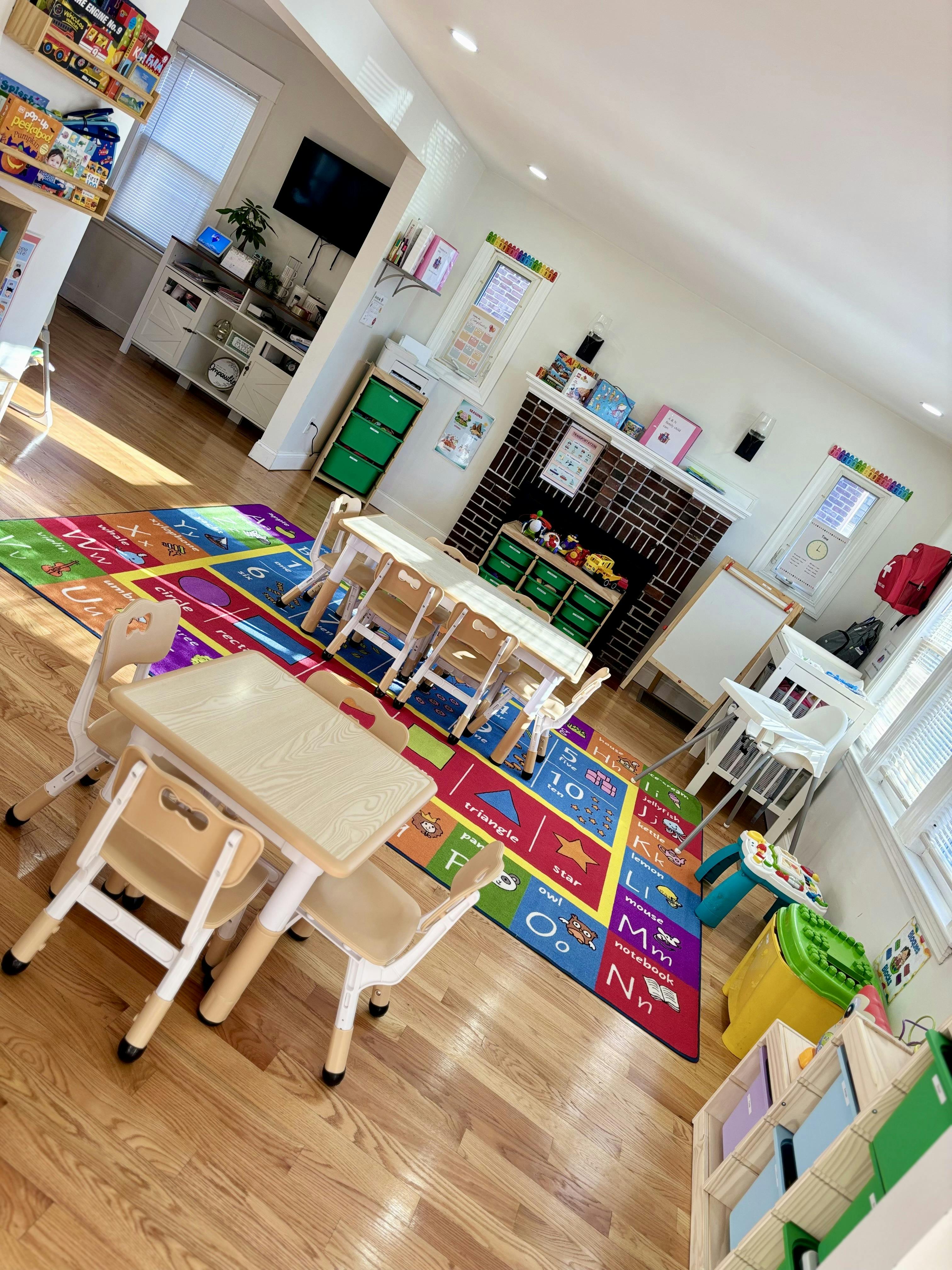 Classroom with small tables and chairs, alphabet rug, and toys