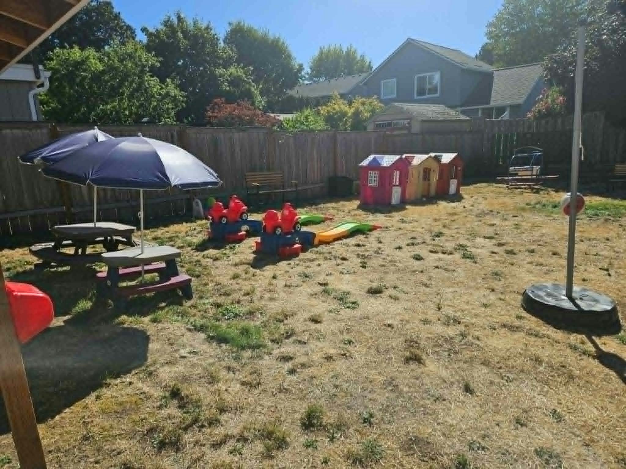 Backyard play area with picnic table, play houses, and ride-on toys