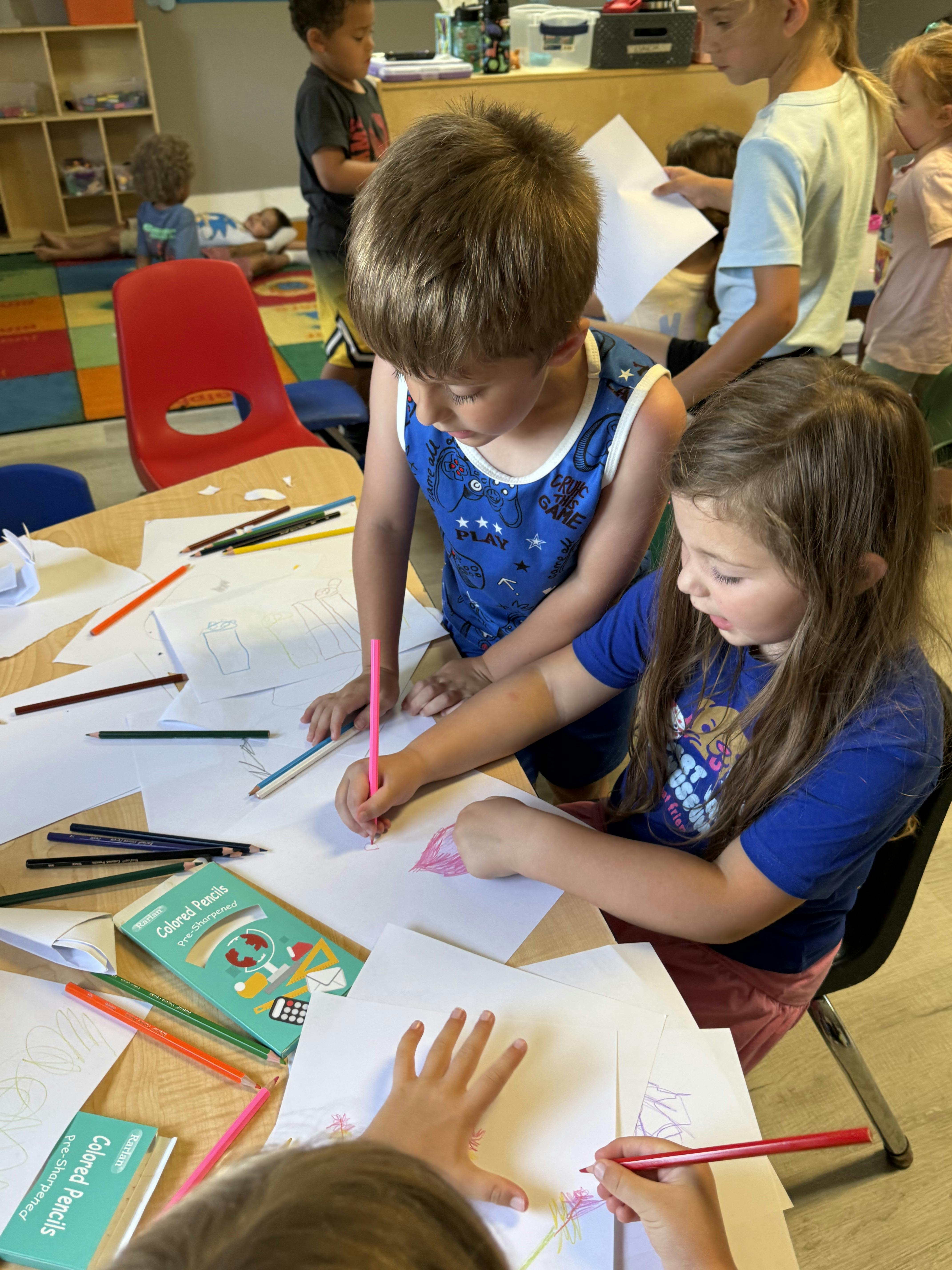 Children drawing with colored pencils at a classroom table