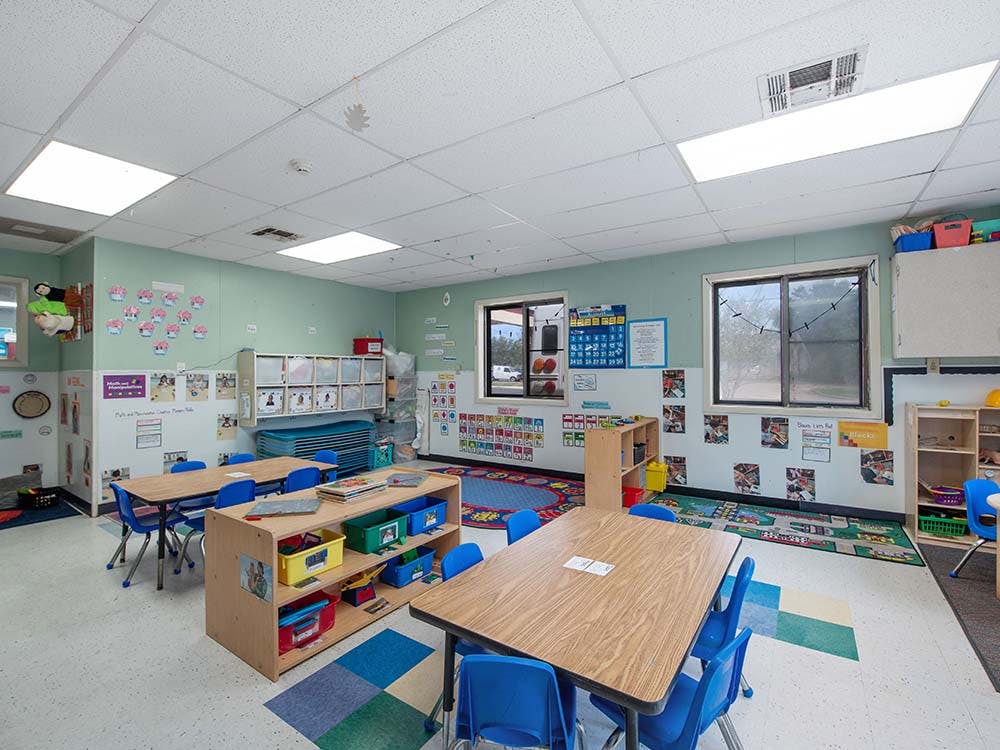 Classroom with small tables and chairs, and learning materials on shelves