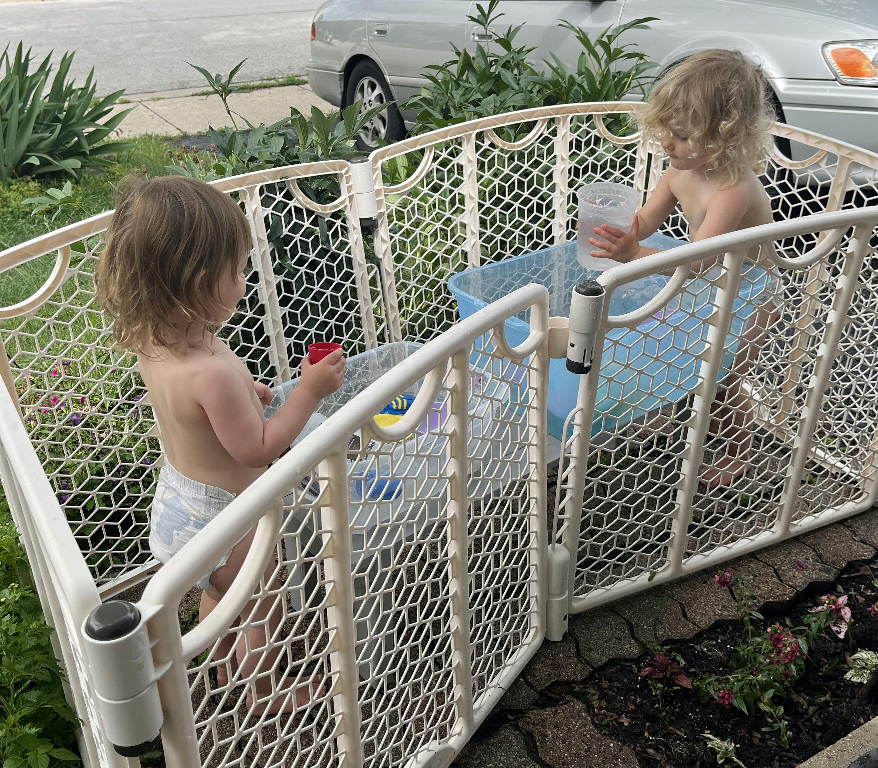 Two children playing with water in a playpen