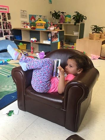 Child sitting in a chair and reading a book