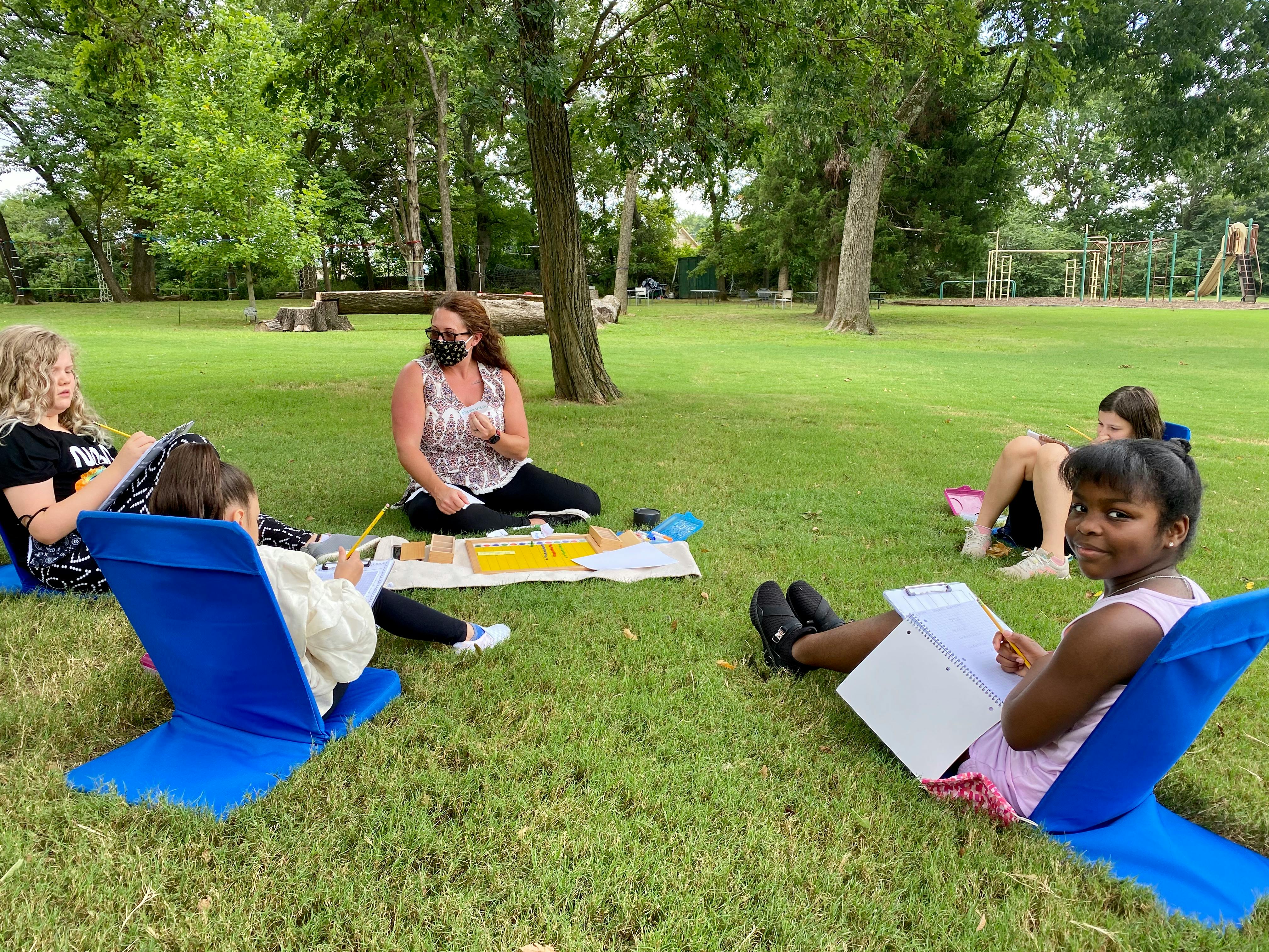 Adult and children sitting on grass in a park