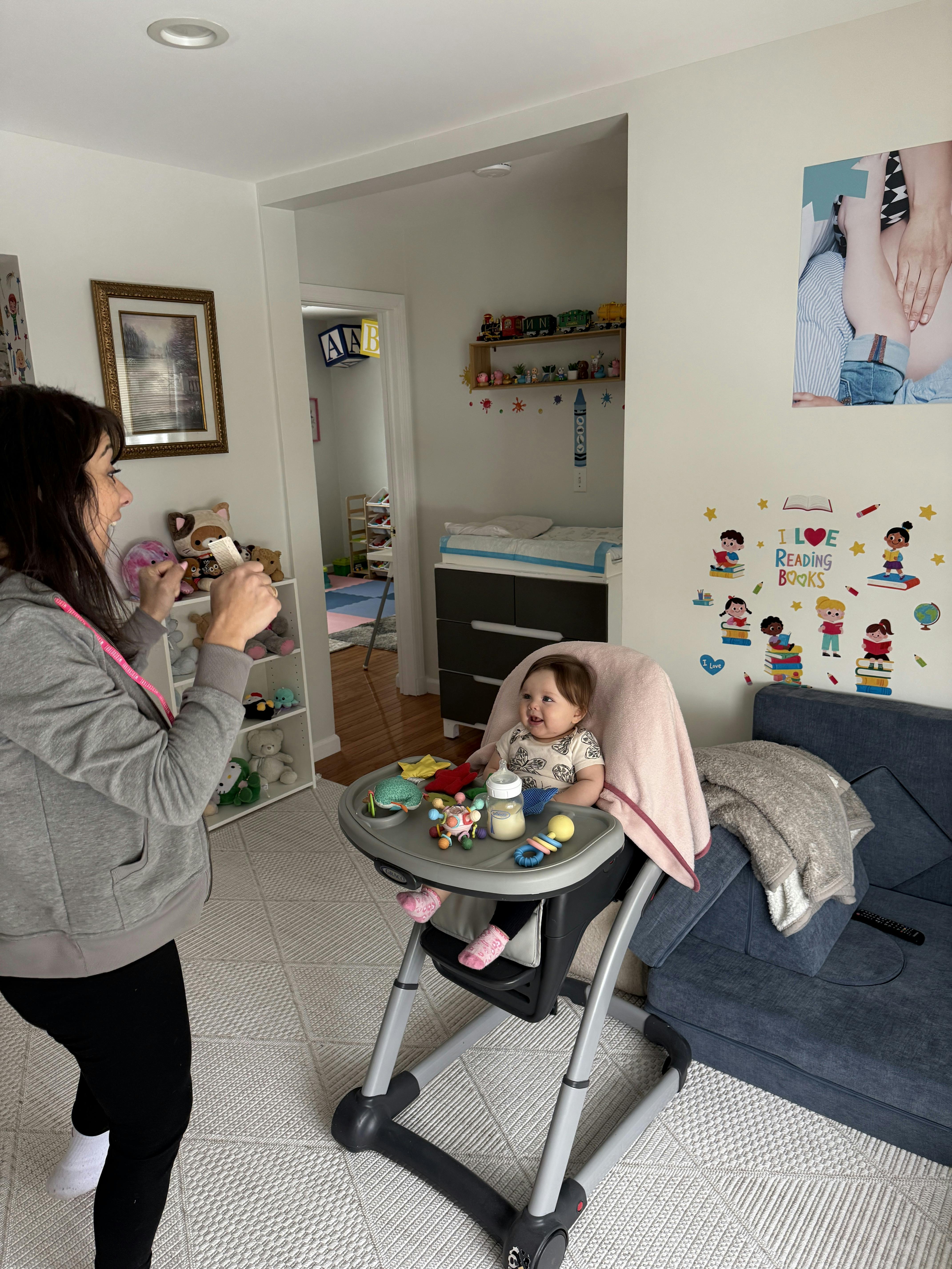 Person holding up a stuffed animal to a child in a high chair