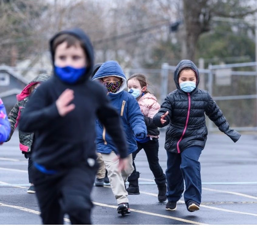 Children wearing face masks running outdoors