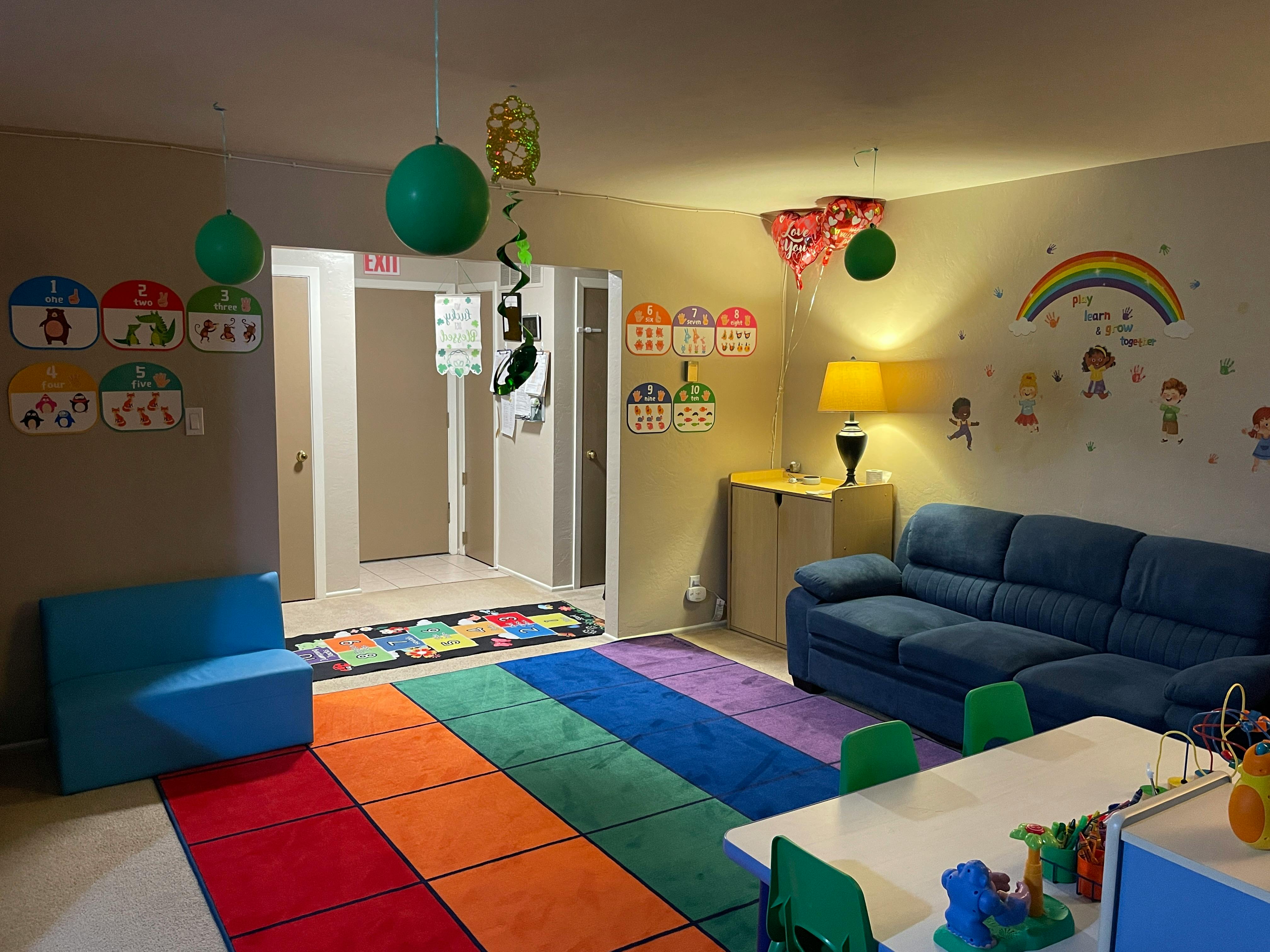 Playroom with a colorful striped rug, blue sofa, and small white table
