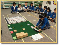 Child playing a board game with other children watching