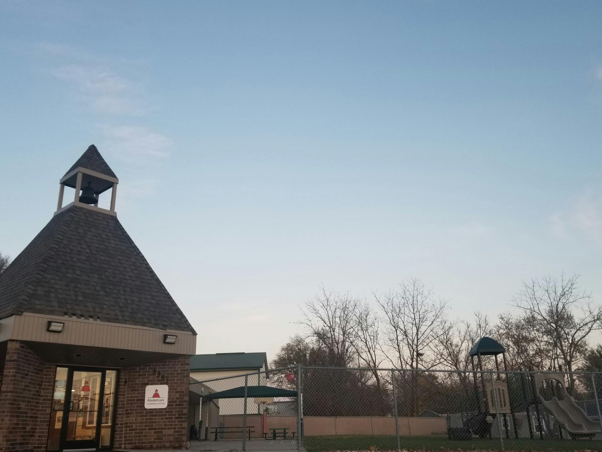 KinderCare Learning Center building with a bell tower and an outdoor playground
