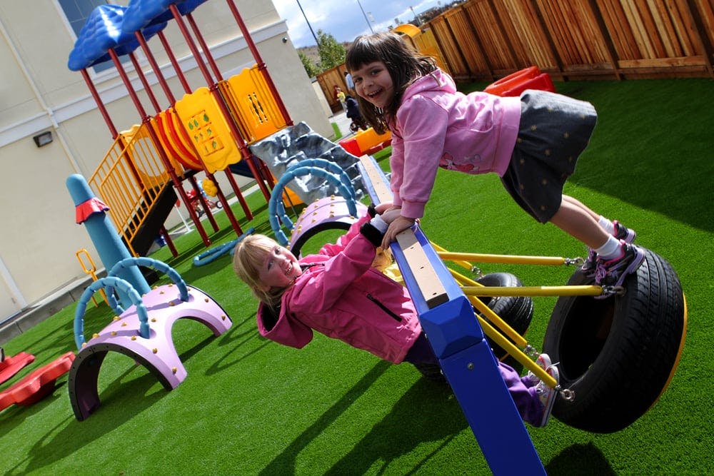 Two children playing on a seesaw in a playground