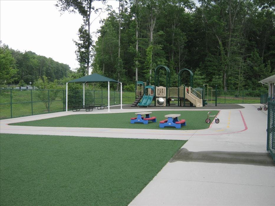 Playground with swings, slides, a green canopy, and colorful picnic tables