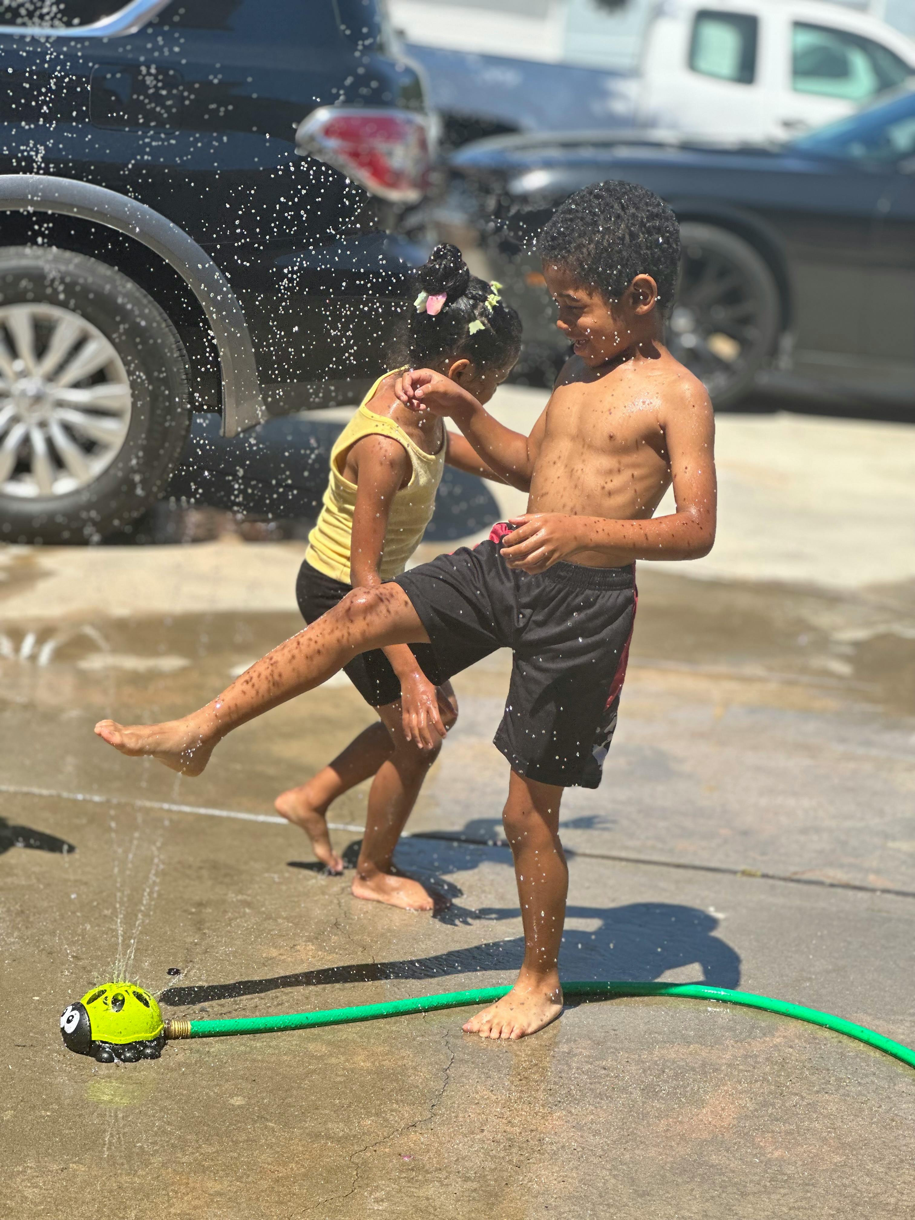 Two children playing in water from a sprinkler
