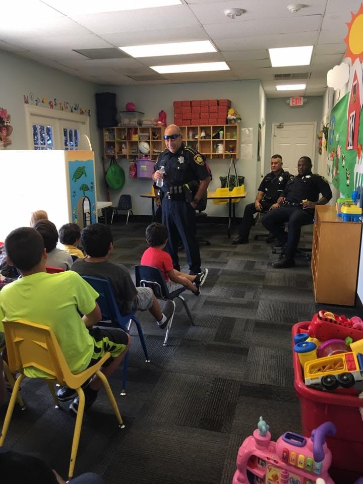 Police officer speaking to children in a classroom, with two other officers seated