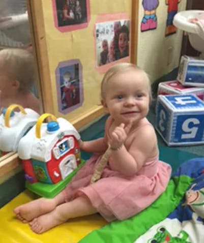 Child sitting on floor next to a toy barn