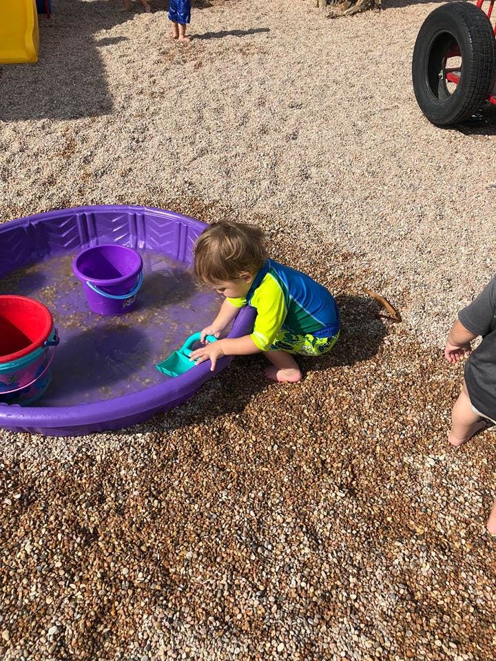 Child playing with a toy in a purple plastic pool