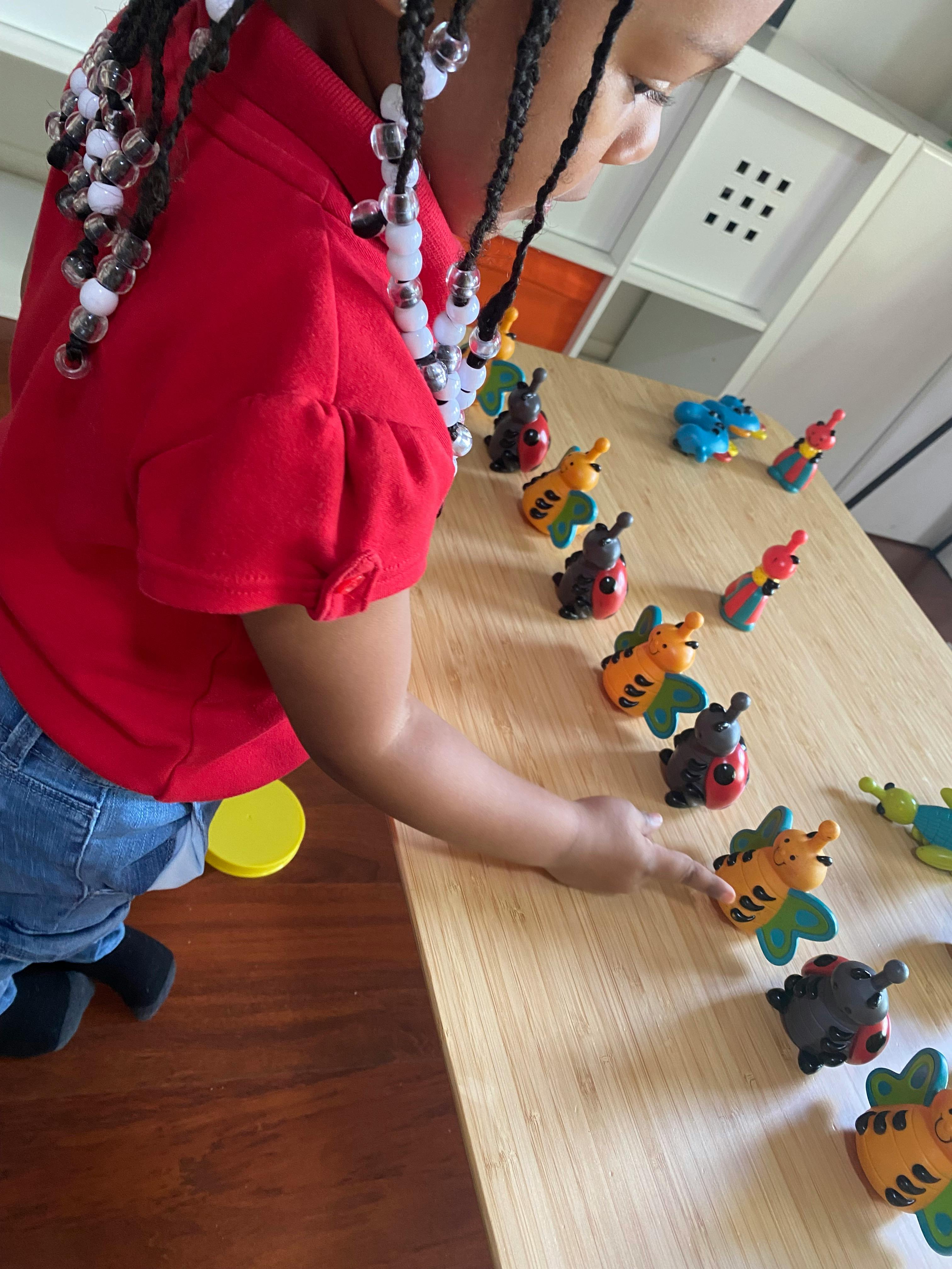 Child playing with insect toys on a table