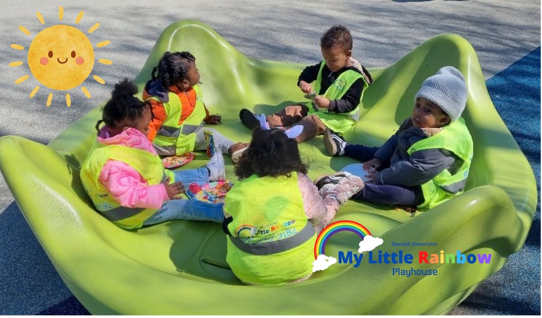 Children in safety vests sitting on a green playground structure