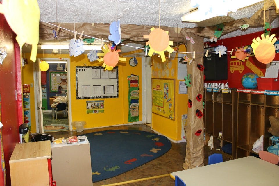 Classroom with yellow walls, blue rug, and paper sun decorations