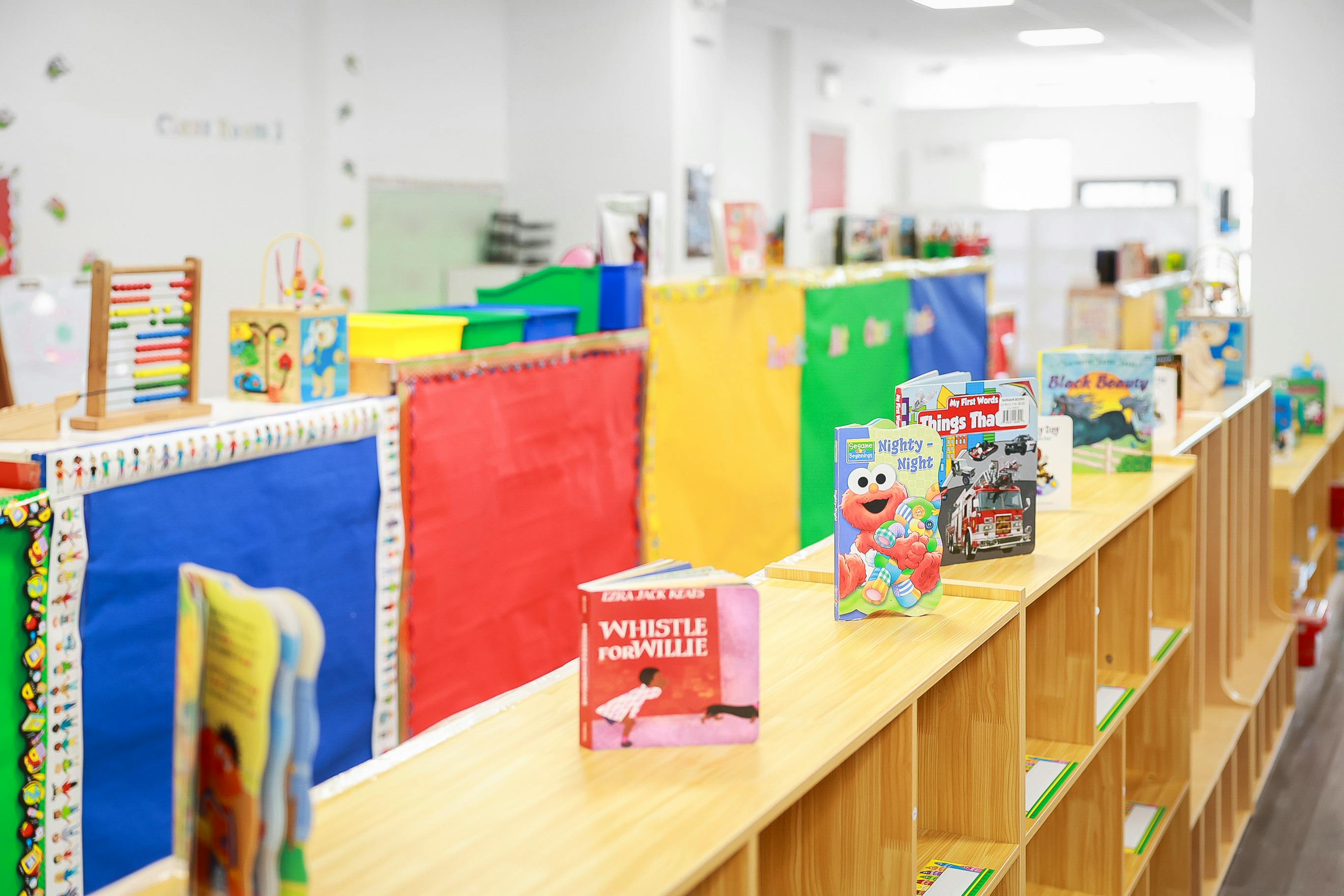 Childrens books displayed on a wooden shelf in a classroom