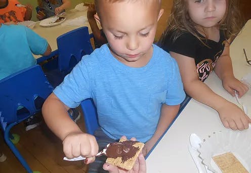 Child spreading chocolate on a cracker
