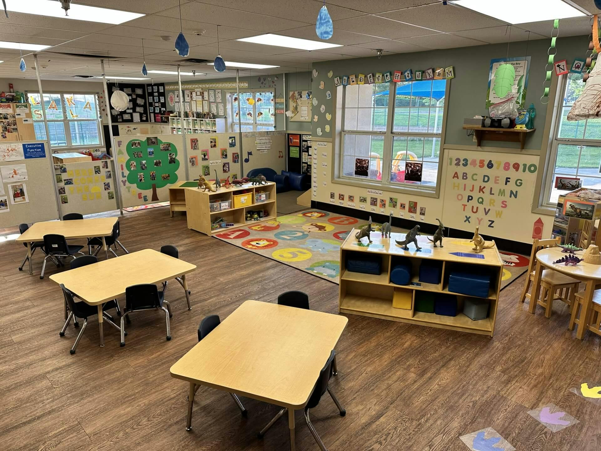 An empty early childhood classroom with small tables and chairs