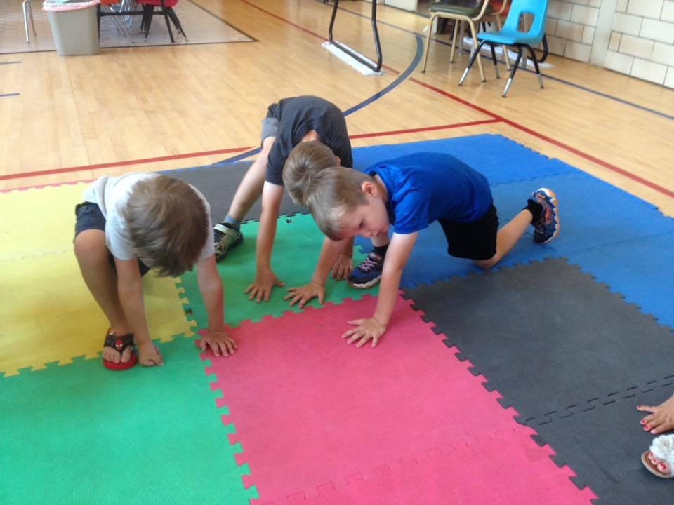 Three children on hands and knees on colorful mats