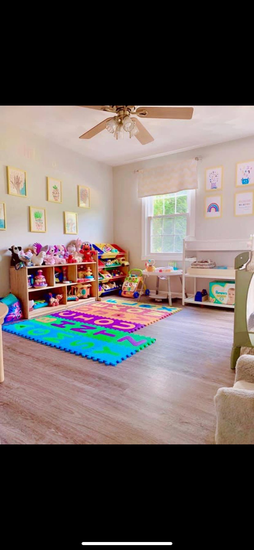 Playroom with colorful alphabet mat, shelves of toys, and window