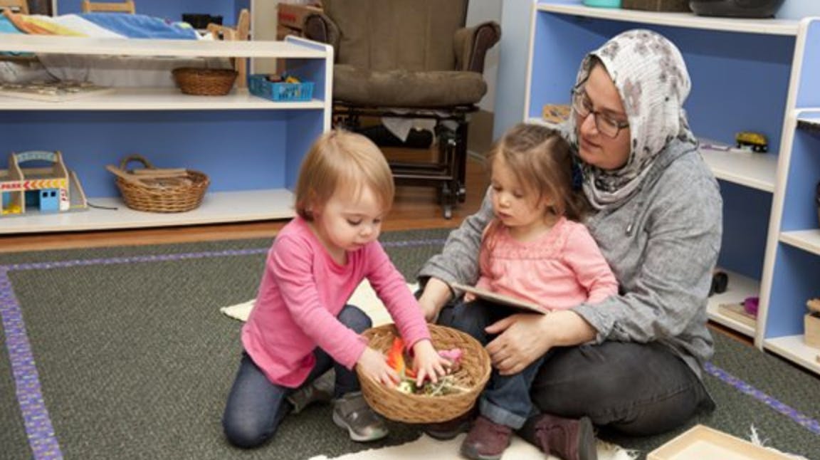 Adult and two children on floor with basket of objects