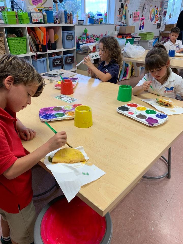 Children painting at a table in a classroom