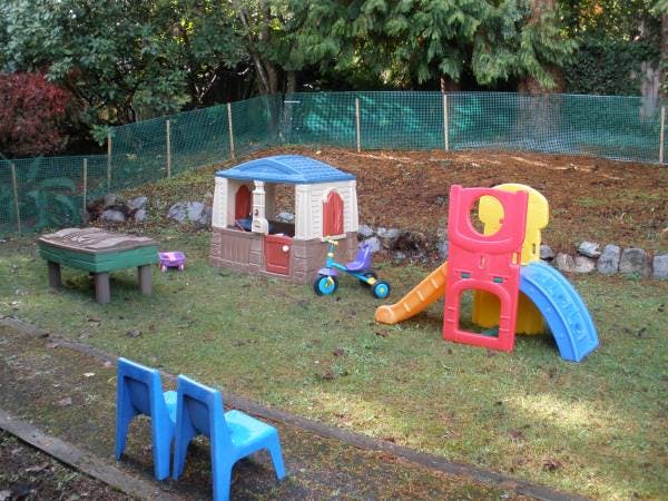 Playground with a playhouse, slide, sandbox, and two blue chairs