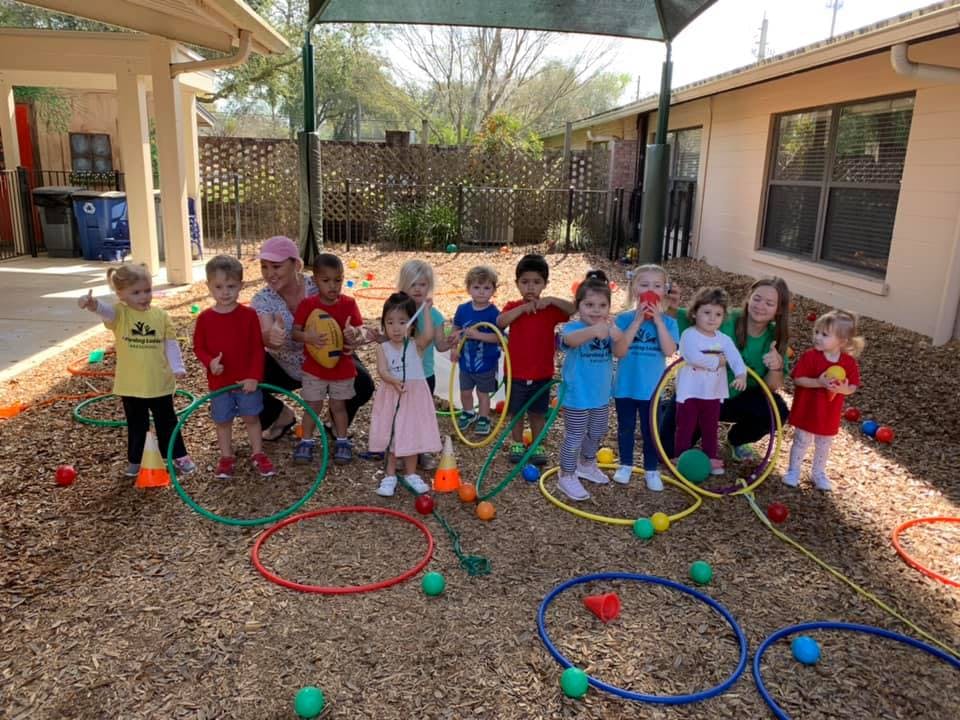 Group of children and adults with hoops and balls on wood chips