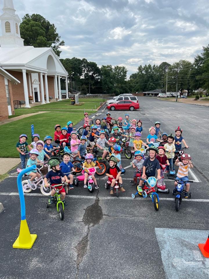 Group of children on bikes and tricycles in a parking lot