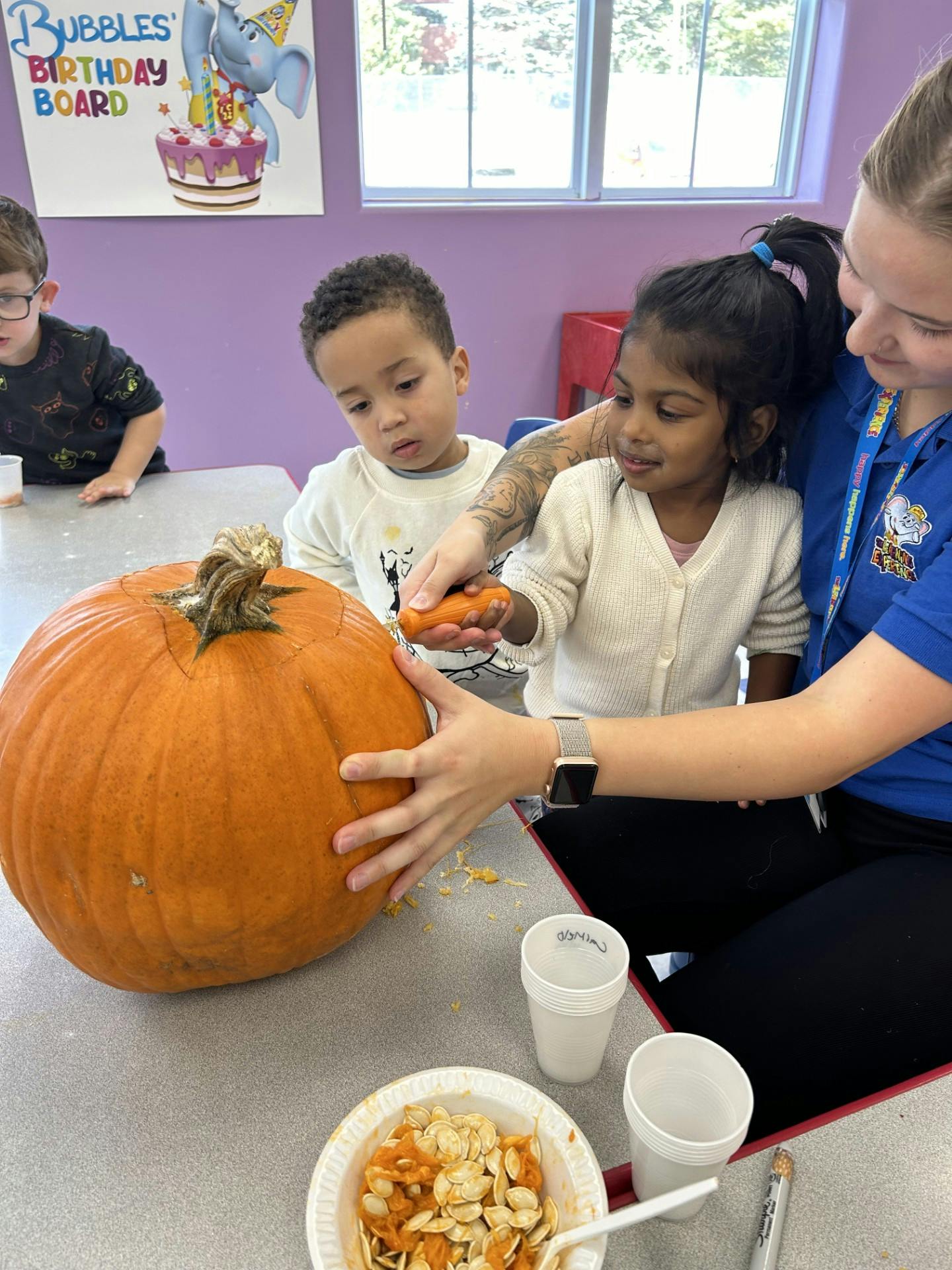 Adult and two children carving a pumpkin