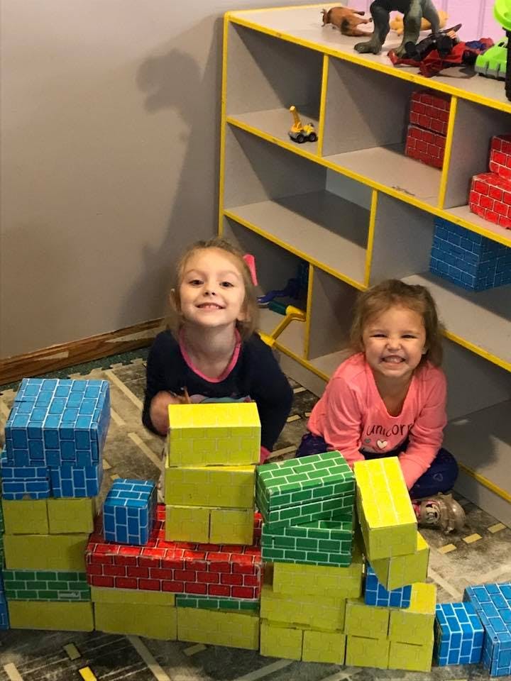 Two children sitting behind block structures