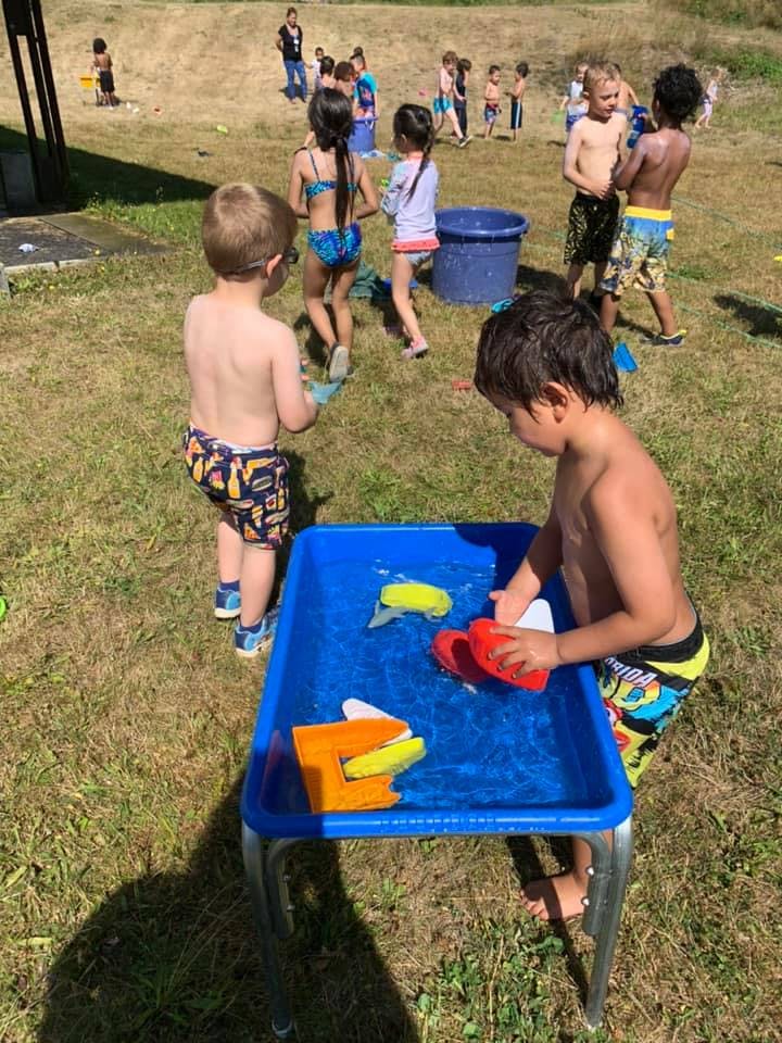 Children playing with water table and toys outdoors