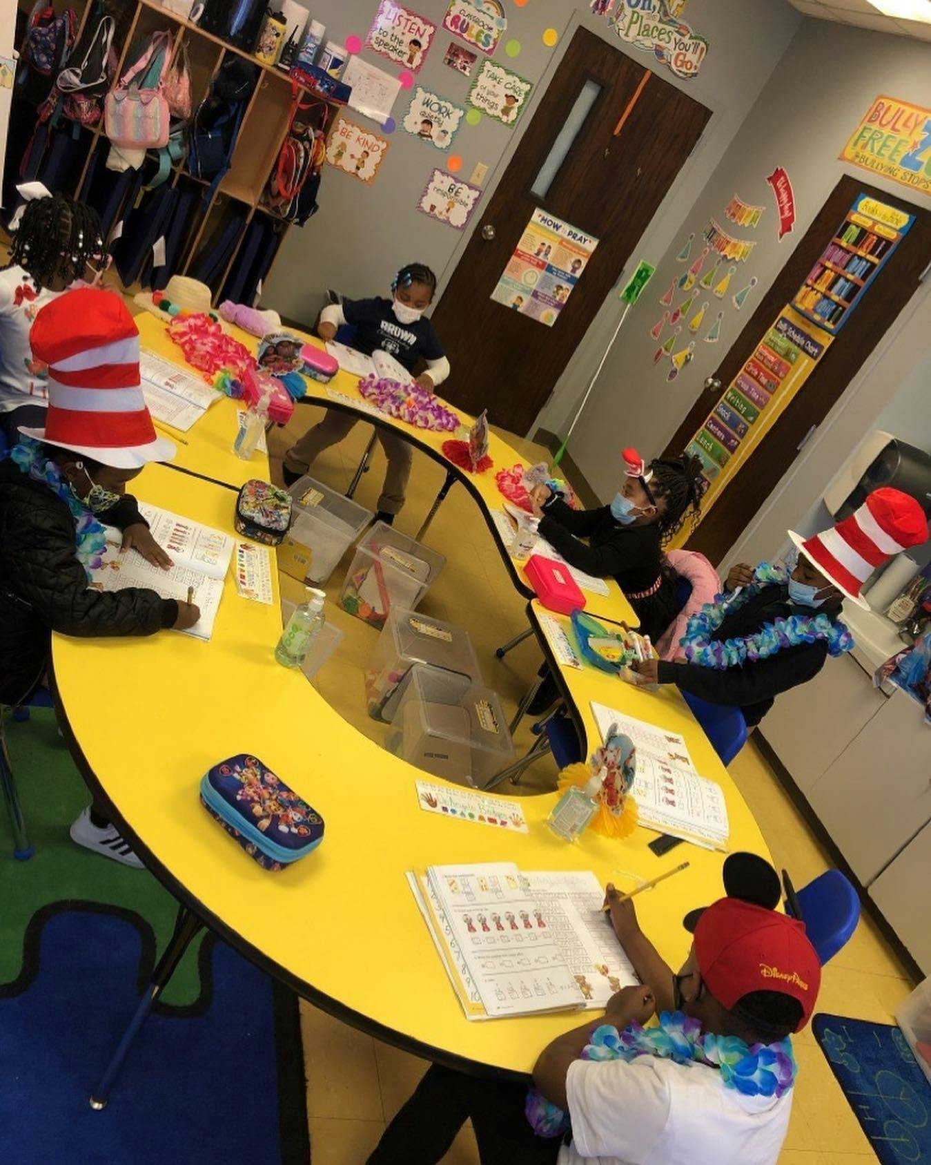 Children sitting at a yellow table in a classroom