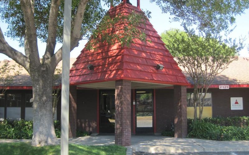 Entrance of a building with a red pointed roof and brick columns