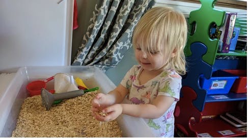 Child playing with grain in a sensory bin