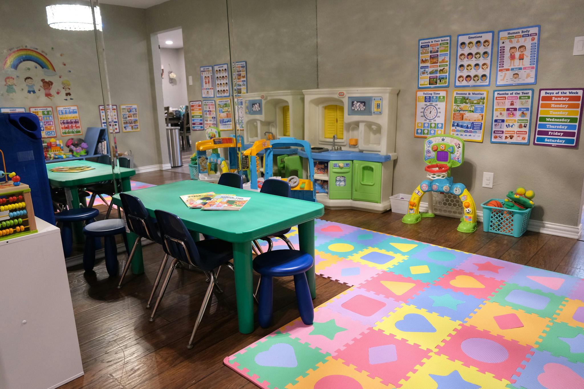 Playroom with green tables, chairs, and colorful floor mats